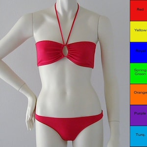May include: A red two-piece swimsuit on a mannequin. The top is a halter style with a central oval detail. The bottom is a classic bikini cut. The color palette includes red, yellow, royal blue, spring green, orange, purple, and turquoise.