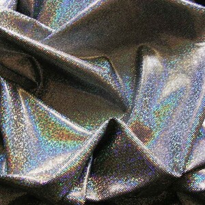 May include: Close-up of a shimmering, iridescent fabric with a metallic silver base. The fabric is heavily textured, with a subtle grid pattern. The folds and creases create highlights and shadows, enhancing the holographic effect. The fabric reflects a rainbow of colors.