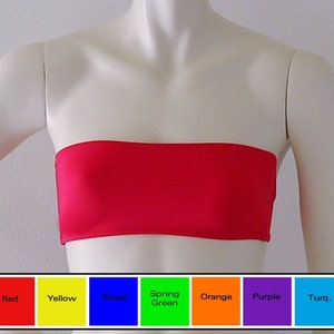 Puede incluir: Un top bandeau rojo brillante sin tirantes. El top está hecho de una tela lisa y brillante. El top se muestra en un maniquí blanco.