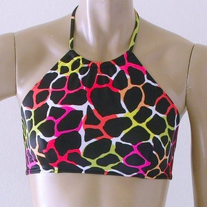 May include: A halter top with a black background and a colorful, abstract pattern in neon pink, orange, yellow, and white. The top has a halter neck and a cropped design.
