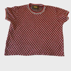 May include: Red and white short-sleeve t-shirt with a repeating pattern of red shapes. The shirt has a striped collar and sleeve cuffs. The tag on the collar reads "FP".