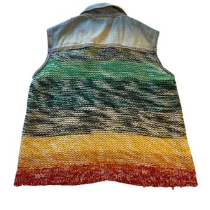 May include: A sleeveless vest with a denim upper and a knitted lower section. The knitted portion features horizontal stripes of green, black, yellow, and red. The vest has a collared neckline.