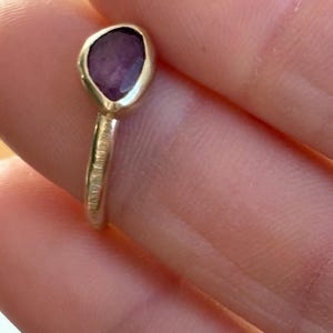 May include: A silver ring with a textured band and a purple gemstone set in a leaf-shaped setting.