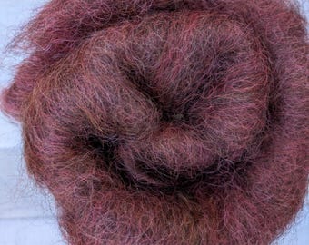 Puede incluir: Primer plano de una masa de fibra de color burdeos oscuro, enrollada firmemente. Las fibras tienen un aspecto suave y texturizado con sutiles variaciones de color, incluyendo toques de marrón y rosa. El material parece ser natural, posiblemente lana o un textil similar.