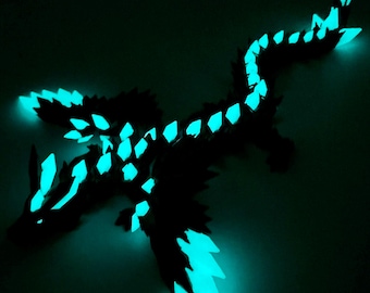 May include: A black dragon figurine with glowing turquoise accents. The dragon has detailed wings, a long tail, and a fierce expression. The turquoise highlights illuminate the edges of the wings, body, and head, creating a striking contrast against the dark background.