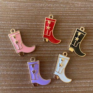 May include: Five gold-tone cowboy boot charms with enamel paint in different colors: red, pink, black, purple, and white. Each boot has a gold star on the front.