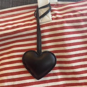 May include: A red and white striped tote bag with a black leather heart charm attached to the handle.