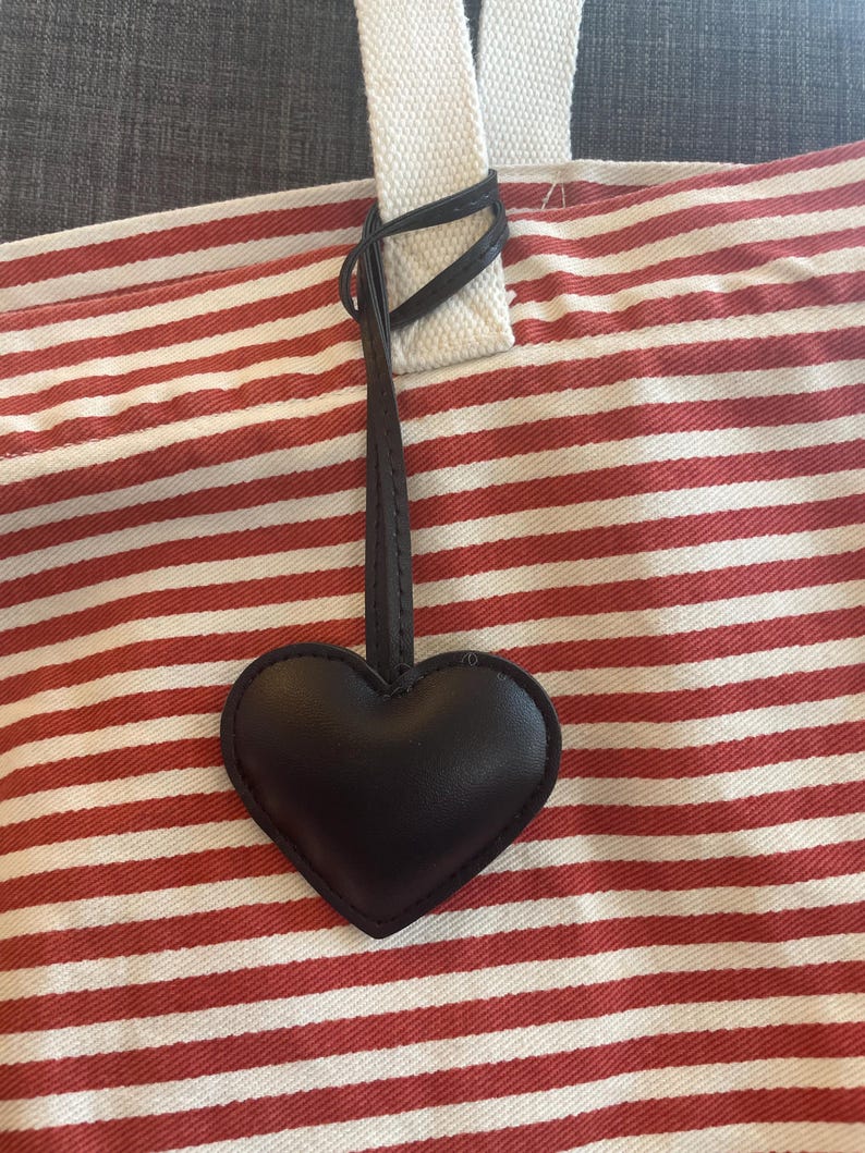 May include: A red and white striped tote bag with a black leather heart charm attached to the handle.