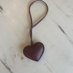 May include: A dark brown leather heart-shaped keychain with a brown leather strap.