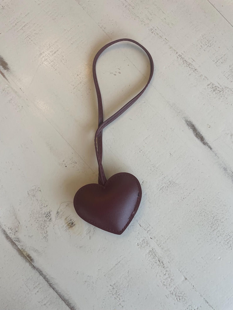 May include: A dark brown leather heart-shaped keychain with a brown leather strap.