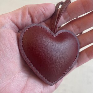 May include: A burgundy leather heart-shaped ornament with a stitched edge and a string for hanging.