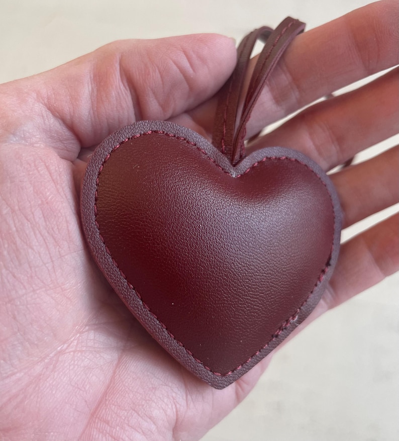 May include: A burgundy leather heart-shaped ornament with a stitched edge and a string for hanging.