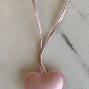 May include: A pink leather heart-shaped keychain with a pink leather strap.