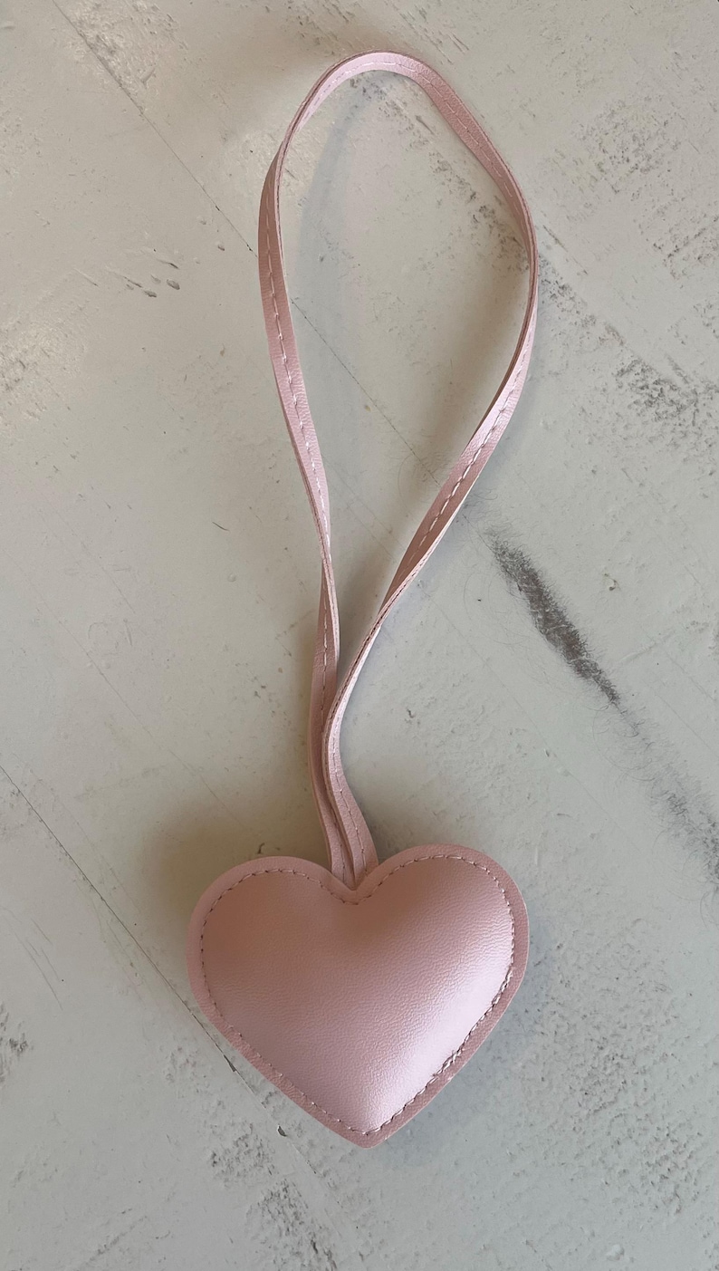 May include: A pink leather heart-shaped keychain with a pink leather strap.