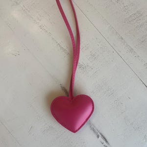 May include: A pink leather heart-shaped keychain with a long pink strap.