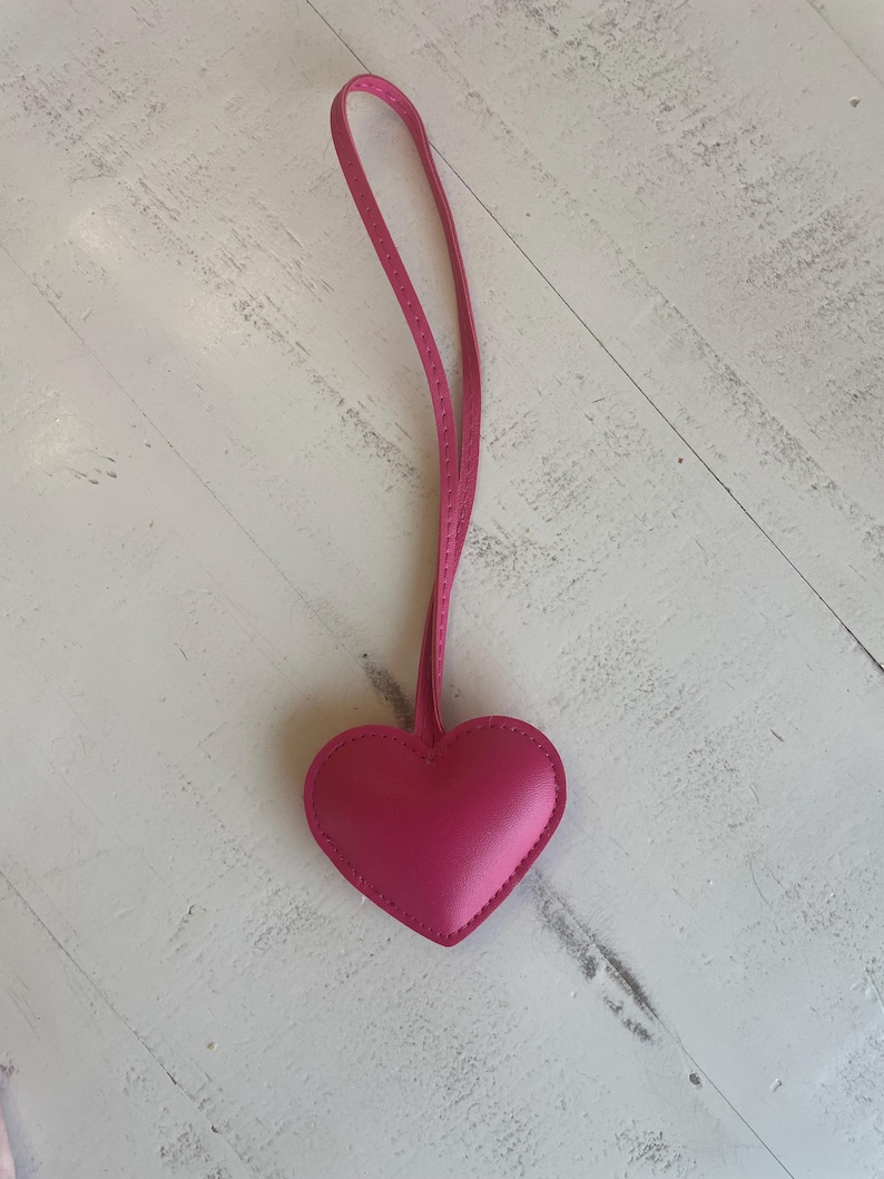 May include: A pink leather heart-shaped keychain with a long pink strap.