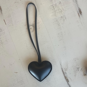 May include: A black leather heart-shaped charm with a black cord.