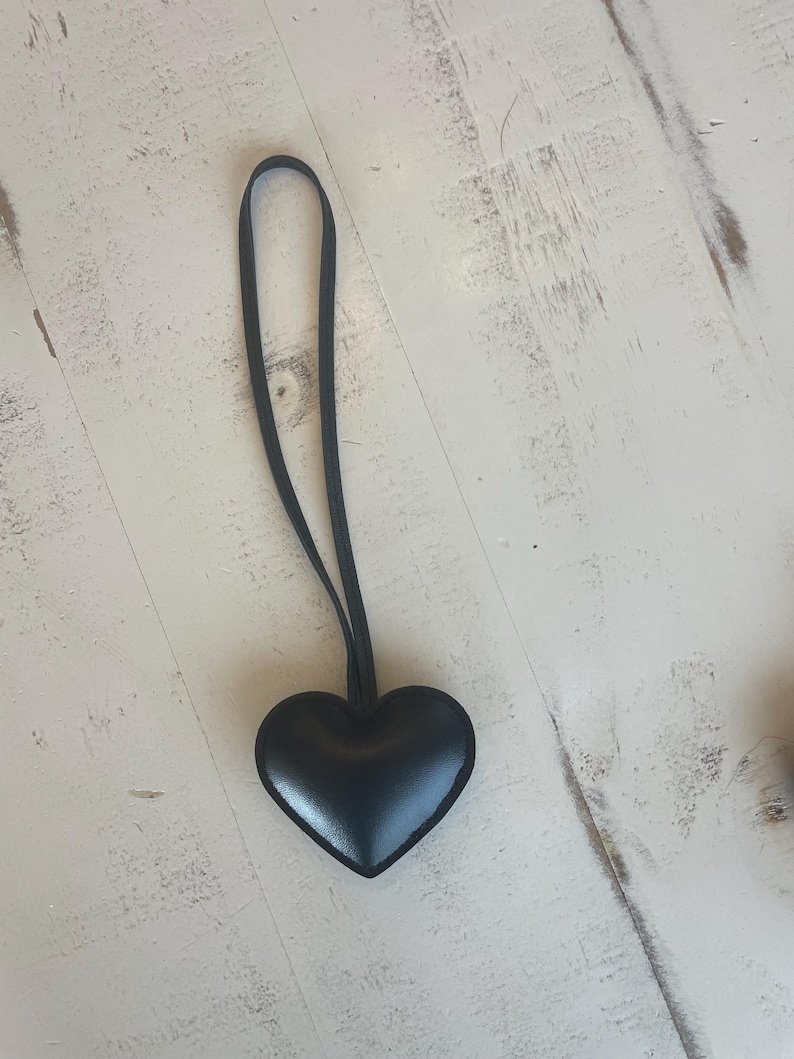 May include: A black leather heart-shaped charm with a black cord.