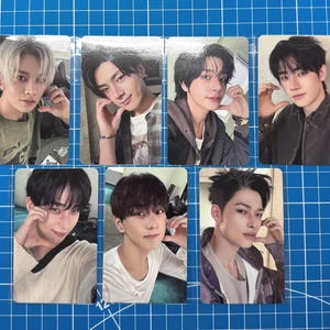 May include: Seven rectangular photo cards featuring portraits of young individuals with various hairstyles and clothing, including sweaters, jackets, and shirts. Each card displays a distinct person posing with a hand near their face, arranged in two rows.