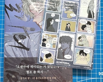 May include: A manga book and sticker sheet set. The book features a grayscale illustration of a male character with white hair. The sticker sheet has various manga panels. Text on the book reads "BOMTOON" and Korean text.