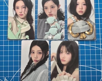 May include: Five rectangular photo cards featuring portraits of a person with long dark hair. The cards display various outfits including a light green accessory, small mint-colored pouches, a large gold-toned ornament, and a pleated white circular item.