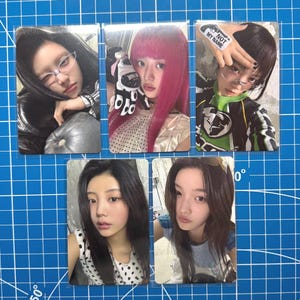 May include: Five photo cards featuring portraits of a person with different hairstyles and outfits. One card has the text "NOT MY NAME" on the person's hand. The cards are on a blue grid background.