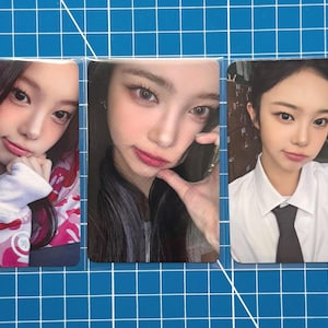 Puede incluir: Tres tarjetas fotográficas rectangulares con retratos de una joven. Las tarjetas están sobre un fondo de cuadrícula azul. La mujer tiene el pelo oscuro y lleva diferentes atuendos en cada foto, incluyendo una camisa blanca y una sudadera con capucha estampada.