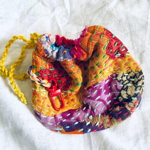 Bolso o cartera pequeña de tela con cordón, bordado a mano y confeccionado en tela reciclada intencionalmente imperfecta.