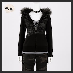 May include: Black zip-up hoodie with faux fur trim on the hood. The hoodie features a skull graphic on the front and is paired with camouflage pants. A black choker necklace is visible. The mannequin is on a white background.
