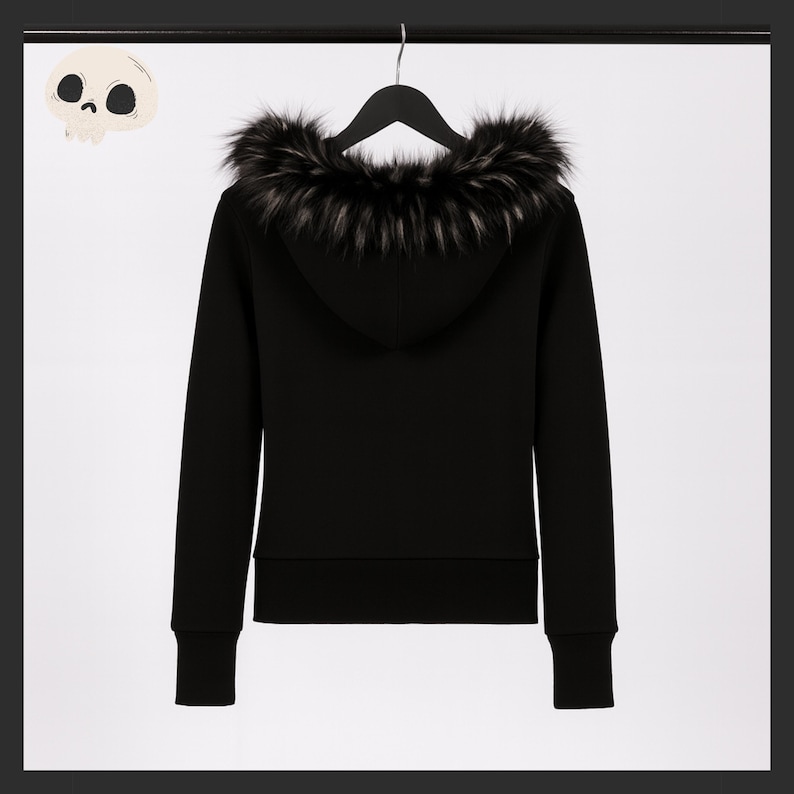 May include: Black hooded sweatshirt with a faux fur trim around the hood. The sweatshirt is hanging on a black hanger against a white background. The cuffs and hem are ribbed. A cartoon skull is in the upper left corner.