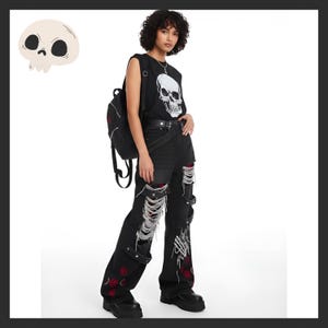 May include: A black sleeveless shirt with a white skull graphic, paired with black ripped jeans featuring red accents and a skeleton hand design. The outfit includes a black backpack and platform boots, creating a gothic punk aesthetic.