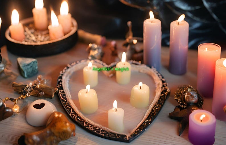 K&ouml;nnte beinhalten: Ein herzf&ouml;rmiges Tablett mit f&uuml;nf brennenden wei&szlig;en Kerzen. Das Tablett ist von anderen Kerzen umgeben, darunter violette, rosa und wei&szlig;e Kerzen. Der Text "Angelika's magic" ist auf dem Tablett sichtbar.