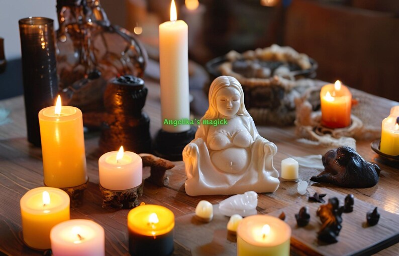 K&ouml;nnte beinhalten: Eine wei&szlig;e Keramikfigur einer schwangeren Frau, die mit ihren H&auml;nden auf ihrem Bauch sitzt. Die Figur ist umgeben von brennenden Kerzen, Kristallen und anderen spirituellen Gegenst&auml;nden. Der Text "Angela's magick" ist auf dem Bild zu sehen.