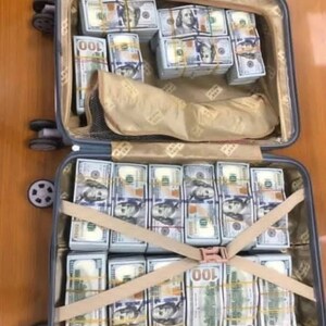 K&ouml;nnte beinhalten: Ein Koffer voller Stapel von US-Dollar-Scheinen im Wert von 100 Dollar, die mit Gurten gesichert sind. Die Scheine sind ordentlich angeordnet und in Reihen gestapelt.