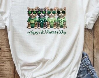 May include: White t-shirt featuring a design of four cats wearing sunglasses and green sweaters. The text "Happy St. Patrick's Day" is printed below the cats.