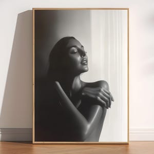 May include: Monochrome framed print. The artwork depicts a person with closed eyes, arms crossed, and head tilted back. The print is in a wooden frame and is displayed against a white wall.