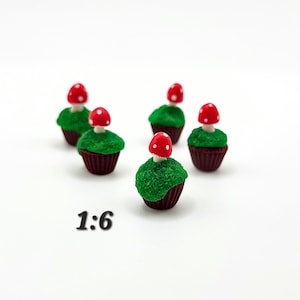 May include: A collection of miniature mushroom-themed cupcakes. Each cupcake features a dark brown base, a green textured frosting, and a red mushroom with white spots. The text "1:6" is printed in black.