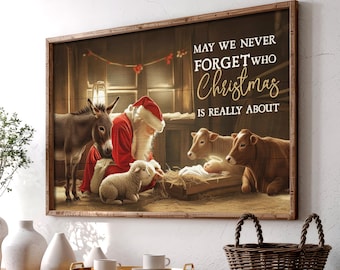 May include: A framed print depicts Santa Claus in a red suit and hat, kneeling near a manger with a baby. A donkey, two cows, and a lamb are also present. The text reads, "MAY WE NEVER FORGET WHO Christmas IS REALLY ABOUT."