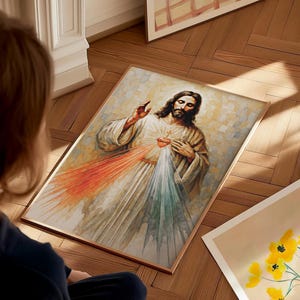 May include: A framed watercolor painting depicting Jesus with a red and white light emanating from his heart. The artwork features a light color palette with a wooden frame. The image is on a wooden floor.