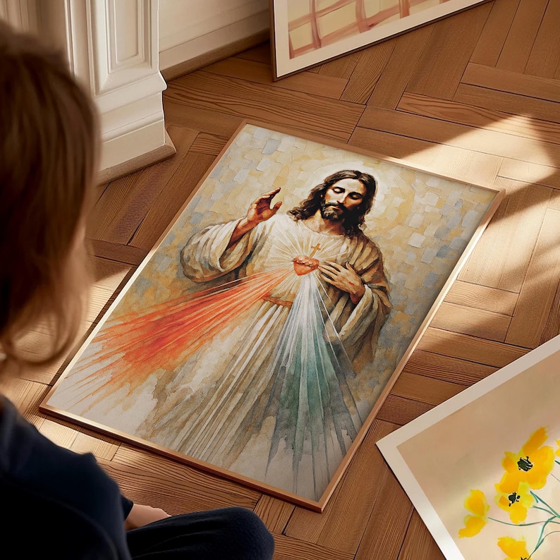 May include: A framed watercolor painting depicting Jesus with a red and white light emanating from his heart. The artwork features a light color palette with a wooden frame. The image is on a wooden floor.
