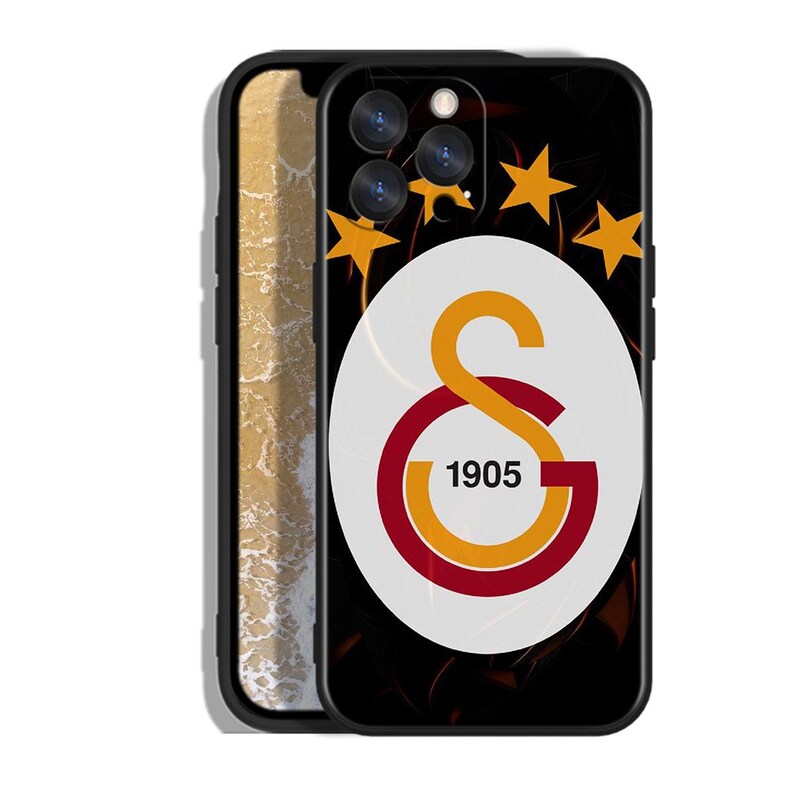 Pode incluir: Capa de telefone preta com o logotipo do Galatasaray. O design inclui um oval branco com o emblema da equipa em laranja e vermelho, o ano de 1905 e estrelas douradas num fundo preto.