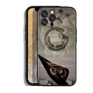 Pode incluir: Capa de telefone preta com um design com o rosto de um le&atilde;o, estrelas e o n&uacute;mero 1905. A capa tem uma borda preta e uma se&ccedil;&atilde;o transparente mostrando uma cena de praia.