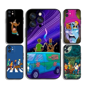 Könnte beinhalten: Vier verschiedene Handyhüllen mit Figuren aus der Zeichentrickserie Scooby-Doo. Die erste Hülle ist schwarz mit einer Zeichnung von Scooby-Doo. Die zweite Hülle ist lila mit einer Zeichnung von Scooby-Doo und Shaggy in einem Van. Die dritte Hülle ist blau mit einer Zeichnung von Scooby-Doo und der Gang. Die vierte Hülle ist schwarz mit einer Zeichnung von Scooby-Doo und der Gang.