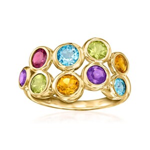 Può includere: Un anello d'oro con un gruppo di pietre preziose colorate. L'anello presenta pietre di taglio ovale in tonalità rosa, blu, giallo, verde e viola. Le pietre preziose sono incastonate in castoni individuali, creando un design vivace.