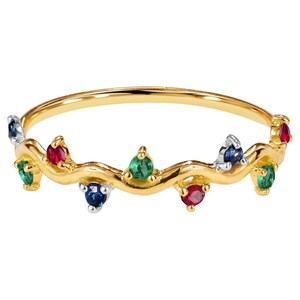 May include: A gold-colored ring with a wavy design, adorned with alternating colorful gemstones. The gemstones include red, green, and blue stones. The ring is a delicate piece of jewelry.