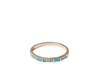 Könnte beinhalten: Ein goldfarbener Ring mit kleinen, rechteckigen, türkis farbenen Steinen, die entlang des Bandes eingesetzt sind. Der Ring hat ein schlichtes, elegantes Design, das für den Alltag geeignet ist. Der Ring wird vor weißem Hintergrund gezeigt.