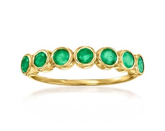 May include: A gold ring featuring seven round, vibrant green emeralds set in individual bezels. The ring has a smooth, polished band and a classic design, perfect for everyday wear or special occasions.