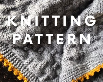 May include: Knitting pattern for a gray cable knit blanket with a yellow crocheted border. The text "KNITTING PATTERN" is displayed on the blanket.