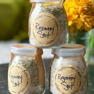 Puede incluir: Tres frascos de vidrio llenos de sal de romero, cada uno con una etiqueta de papel marr&oacute;n que dice "Rosemary Salt".