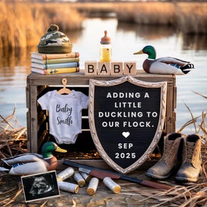 May include: A baby announcement scene with a wooden crate holding a baby bottle, blocks spelling "BABY", and a sign that reads "Adding a little duckling to our flock. Sep 2025." Includes a onesie, boots, and a toy duck.
